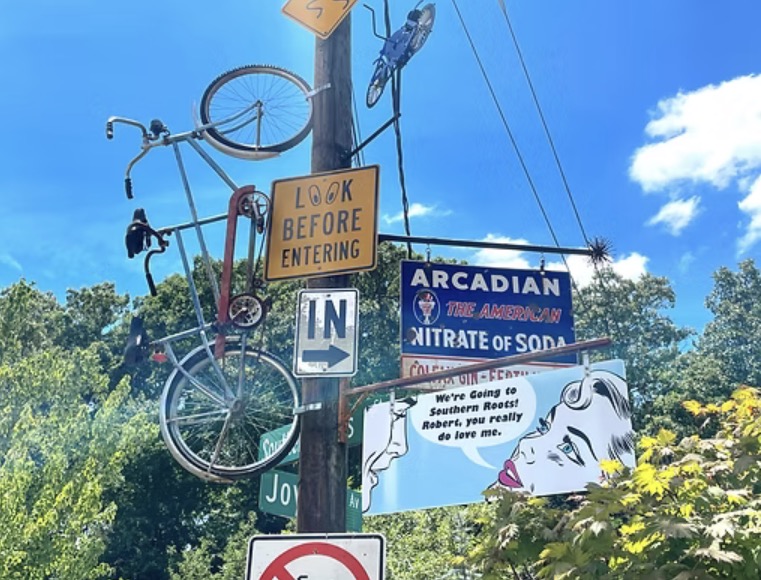 Vintage signs and an old bicycle mounted on a pole at Southern Roots Garden Center in Belmont NC